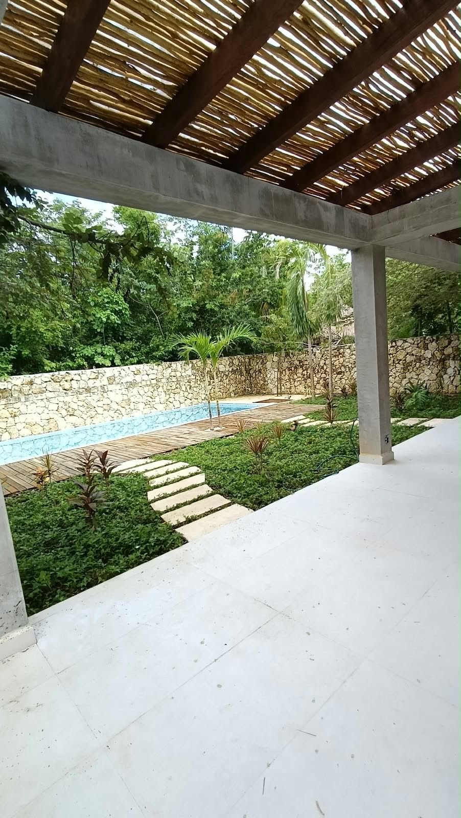 Jardín y alberca de una casa privada bajo una pérgola de madera